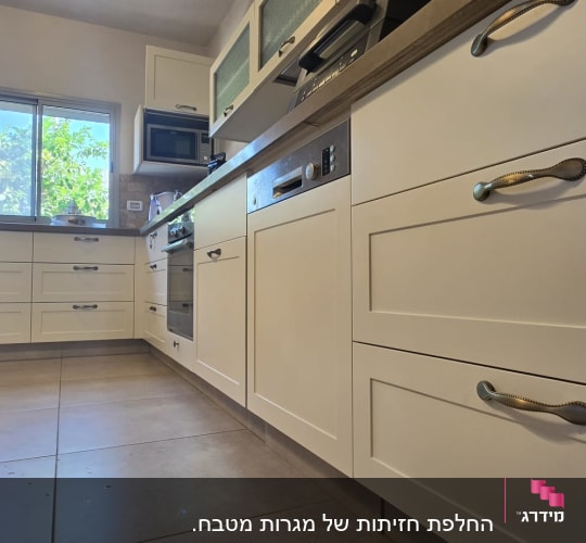 מטבח עם ארונות לבנים וידיות מתכת